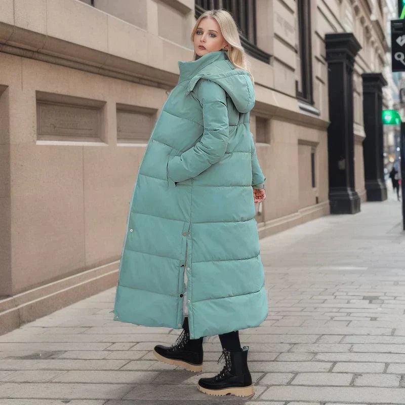 Frau in mintgrünem Daunenmantel, Wintermode, Stadtstraße, schwarze Stiefel, stilvoll, warm.