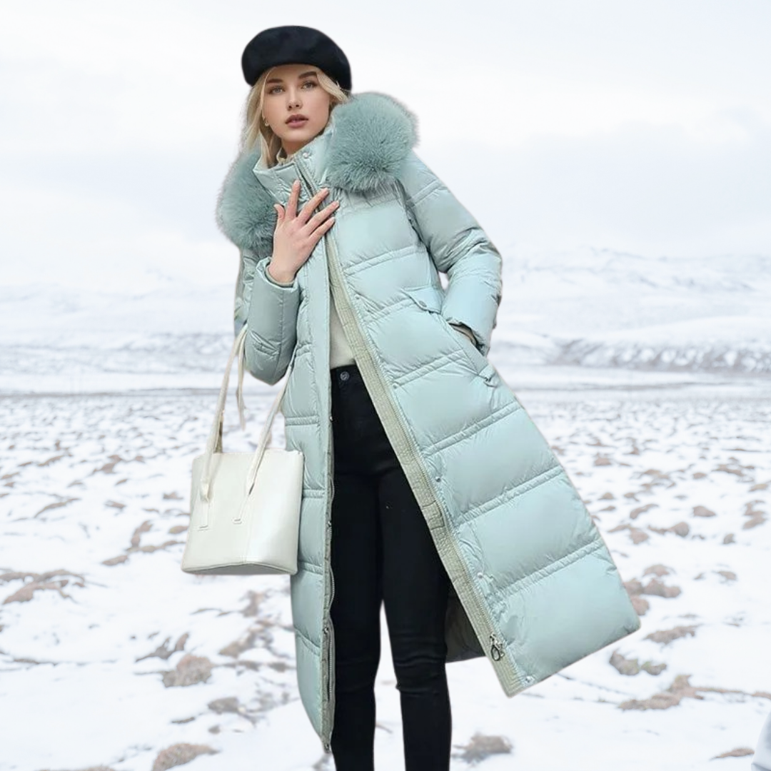 Frau in mintgrünem Daunenmantel mit Fellkragen, Wintermode, schneebedeckte Landschaft.