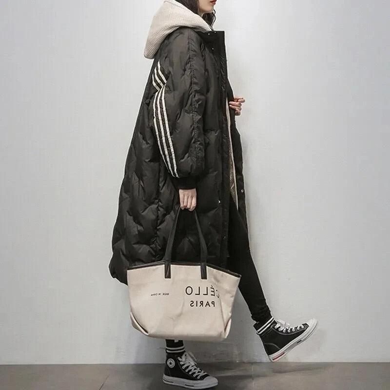 Frau in schwarzem Daunenmantel mit Kapuze, trägt beigen "Hello Paris" Shopper, lässiger Stil.