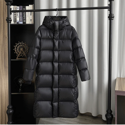 Schwarzer Daunenmantel mit Kapuze, lang, warm, Wintermode, hängend vor Bücherregal.