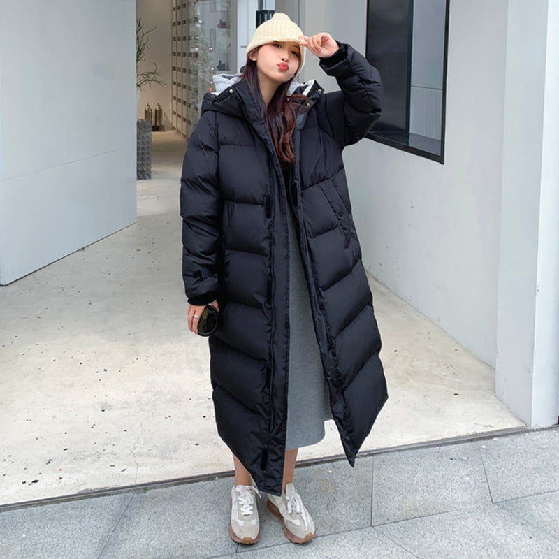 Frau in schwarzem Daunenparka, Wintermode, lange Jacke, draußen, beige Mütze, lässiger Stil.