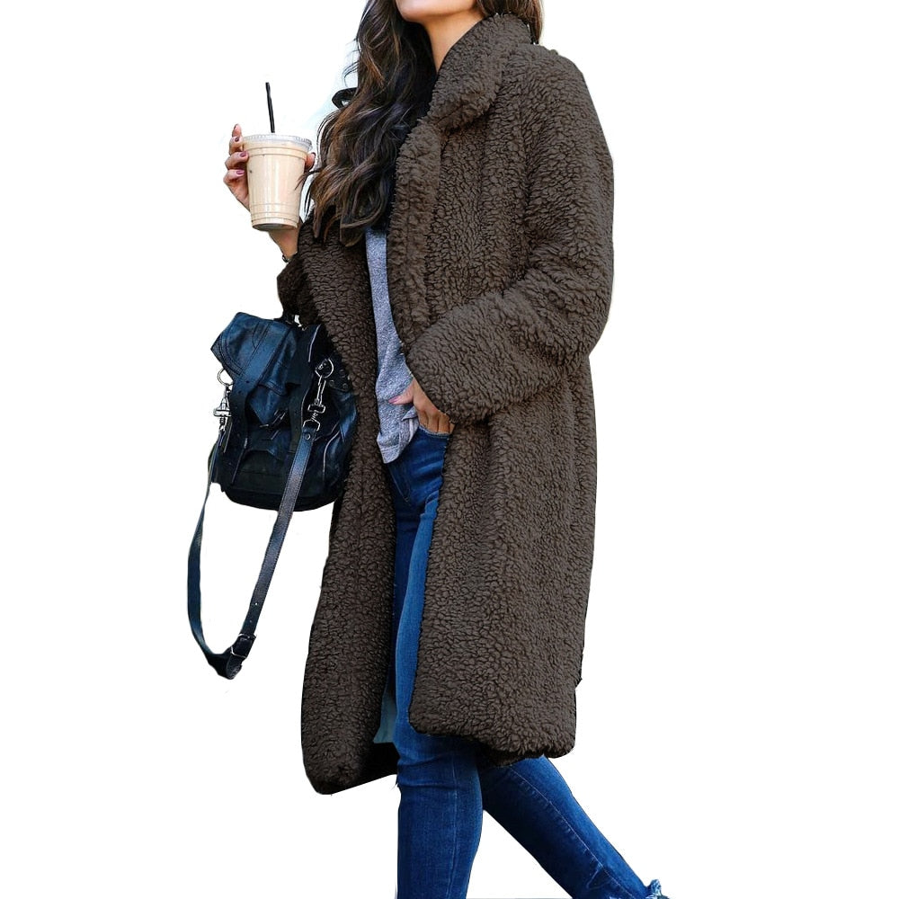 Frau in braunem Teddy-Mantel, Jeans, mit schwarzer Tasche und Getränk, Wintermode.
