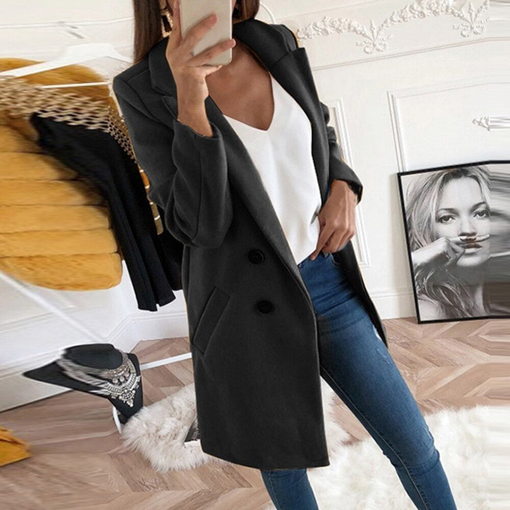 Frau im schwarzen Mantel, weißem Top und blauer Jeans, modisch, stilvoll, Innenraum.