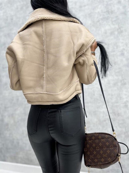 Frau in beiger Lederjacke mit Sherpa-Futter, schwarze Hose, braune Designer-Handtasche.
