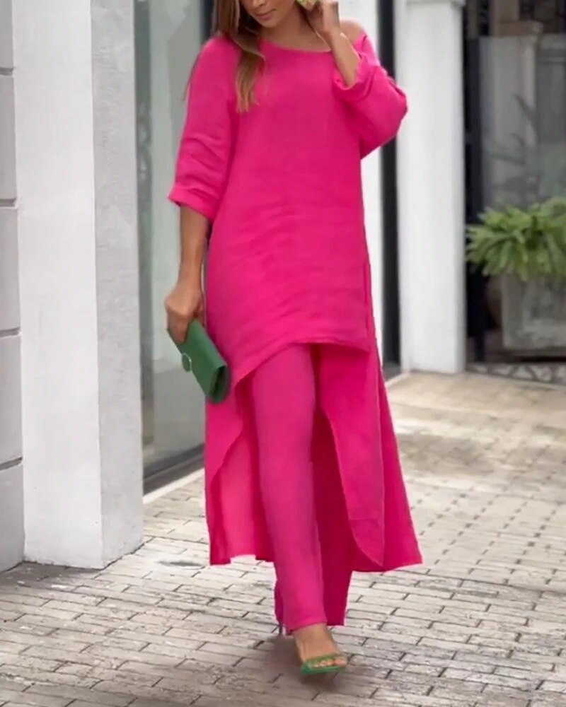 Frau in pinkem Kleid und Hose, hält grüne Clutch, modisch, elegant, Sommermode, Straße.