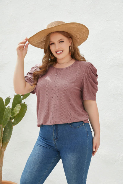 Frau in rosa Spitzenbluse und Jeans, trägt Strohhut, lächelt, steht neben Kaktus, Sommermode.