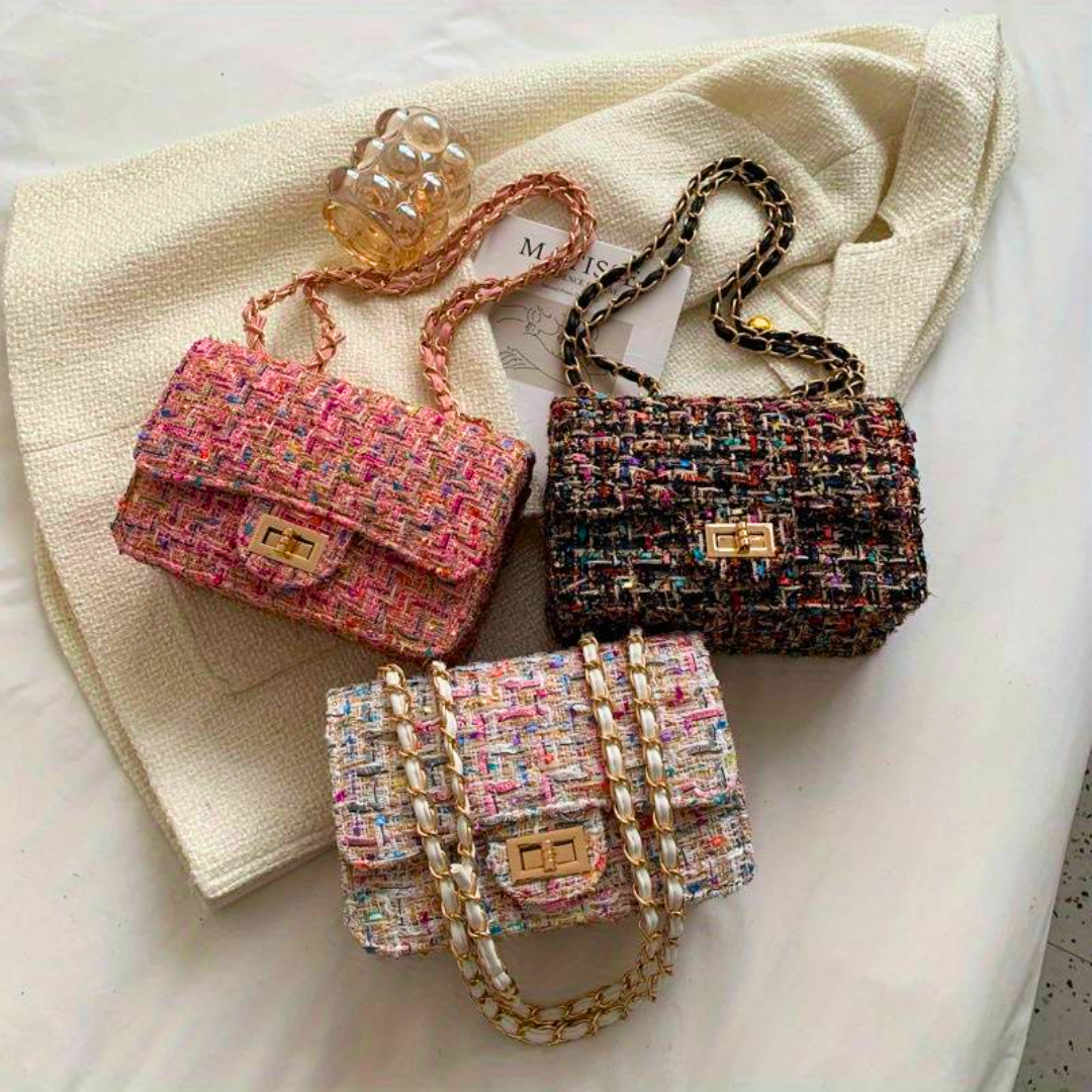Drei bunte Tweed-Handtaschen mit Kettenriemen auf weißem Stoff, modisch und elegant.