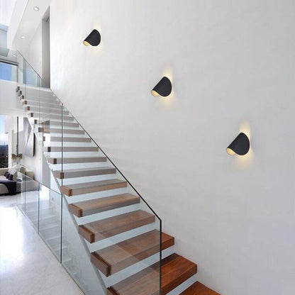 Moderne Treppenhausbeleuchtung, schwarze Wandlampen, minimalistisches Design, Holzstufen.