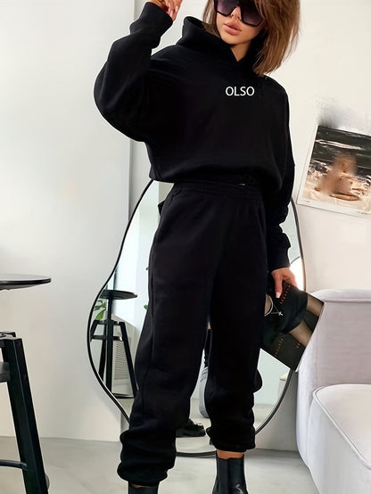 Frau in schwarzem Hoodie und Jogginghose, OLSO-Logo, modisch, lässig, Spiegel, Sonnenbrille.