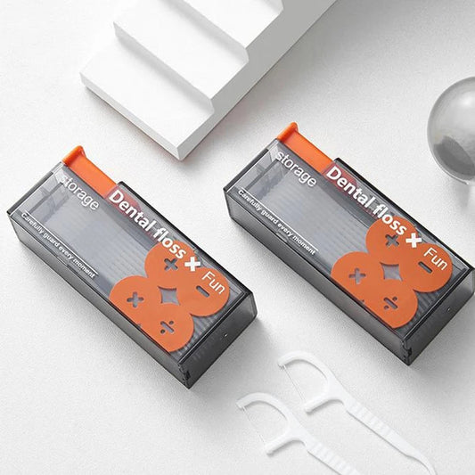 Zwei schwarze Zahnseideboxen mit orangefarbenem Deckel auf weißem Hintergrund, Zahnpflegeprodukte.
