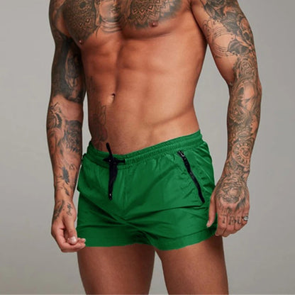 Mann in grüner Sportshorts, tätowiert, muskulös, Fitnessmode, Herrenbekleidung, Sportbekleidung.