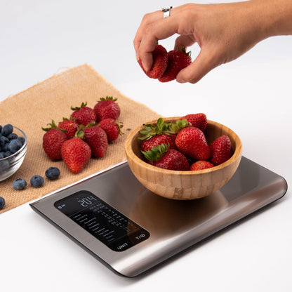 Digitale Küchenwaage aus Edelstahl mit Erdbeeren in Holzschale, moderne Lebensmittelwaage.