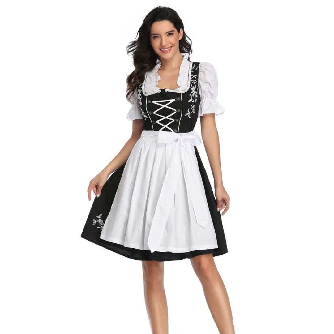 Frau im traditionellen schwarzen Dirndl mit weißer Schürze und Stickereien, Oktoberfest-Kleidung.