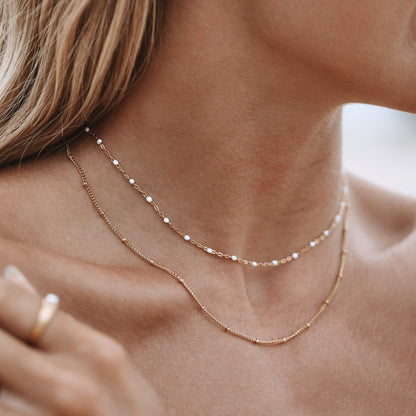 Frau trägt doppelte minimalistische Choker-Halskette aus Gold, eleganter Schmuck, Nahaufnahme.