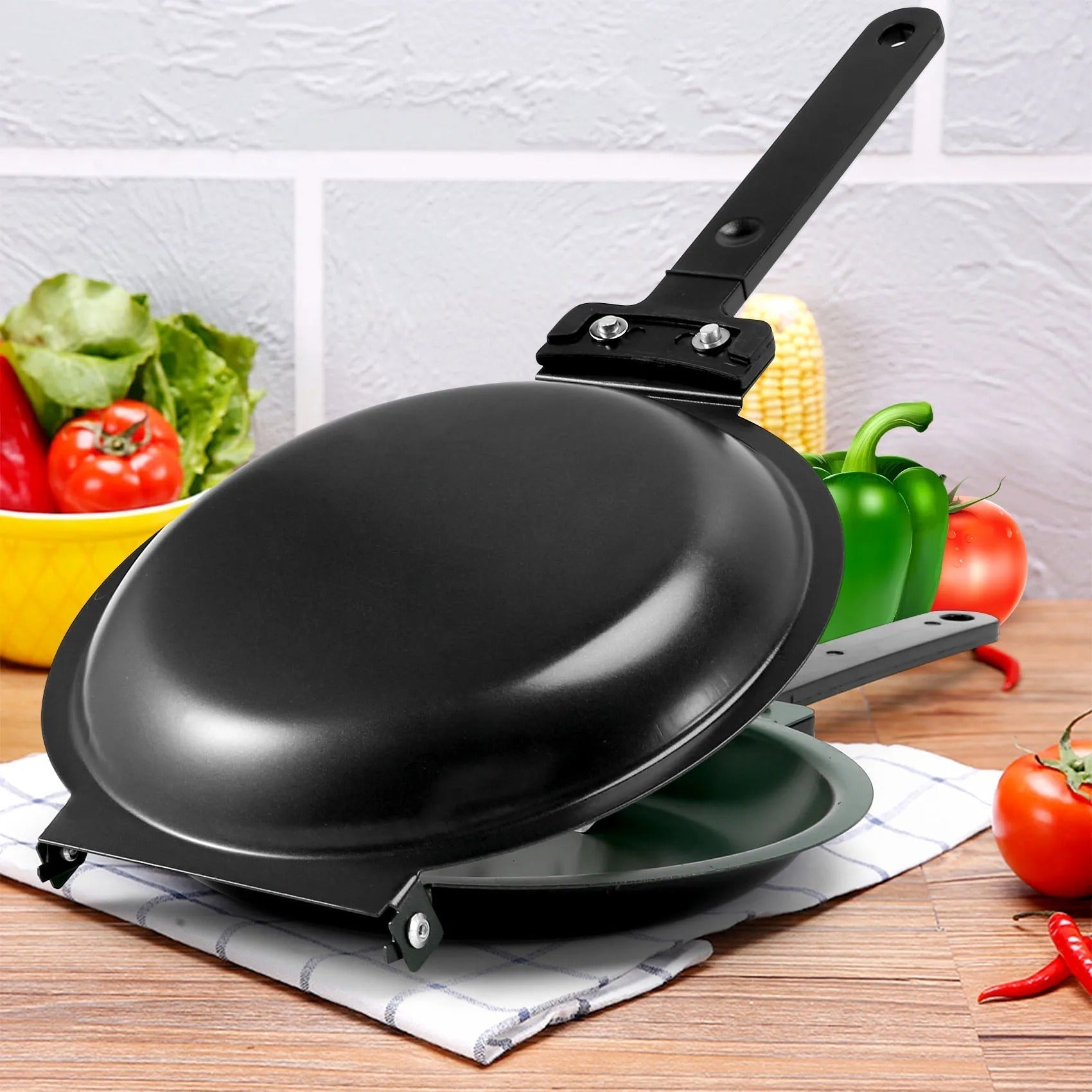Schwarze Antihaft-Pfanne mit Griff, ideal für gesundes Kochen, auf Küchentuch mit Gemüse.