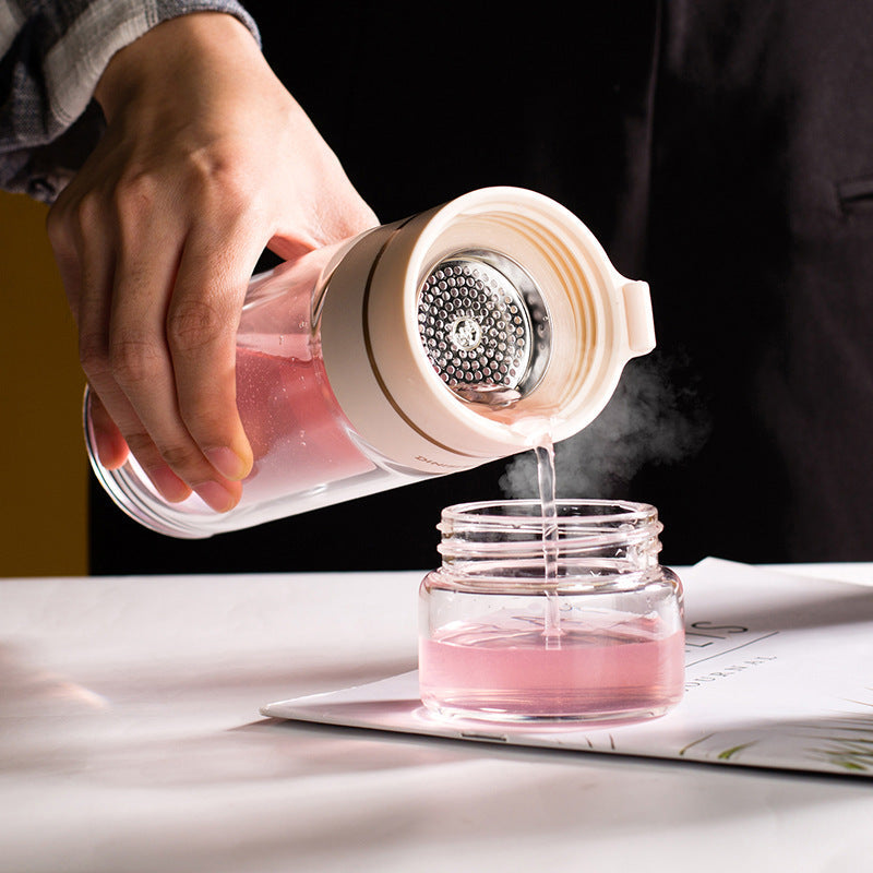 Hand gießt rosa Getränk aus Glasflasche mit Sieb in Glas, Küchenzubehör, modern, transparent.