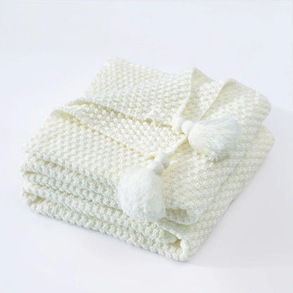 Weiße Strickdecke mit Quasten, weiches Baumwollmaterial, gemütliche Wohnaccessoires.