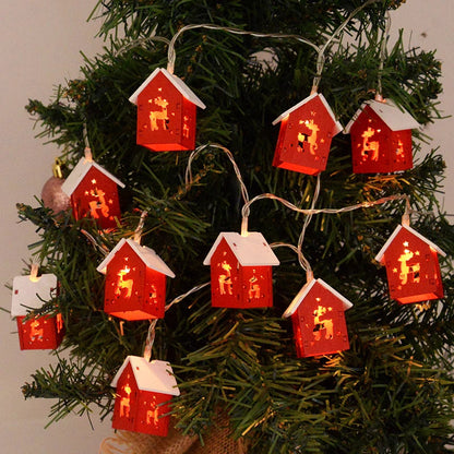 Rote LED-Weihnachtslichter in Hausform mit Rentiermotiv auf Tannenbaum.