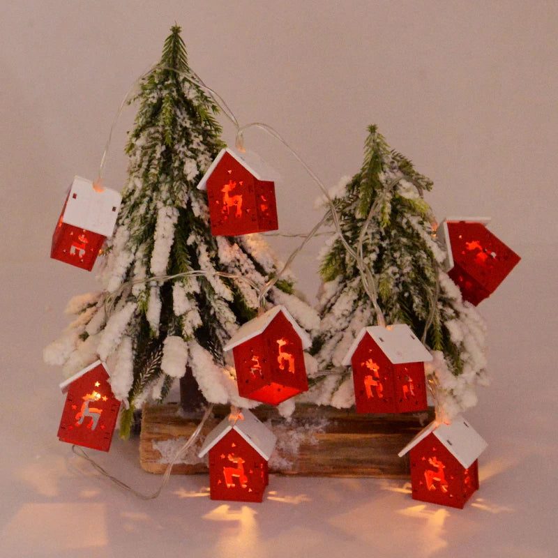 Weihnachtslichterkette mit roten Häuschen, Tannenbaum, Schnee, festliche Dekoration.