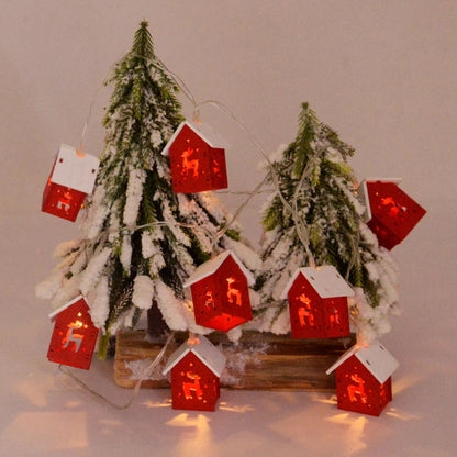 Weihnachtslichterkette mit roten Häuschen, Tannenbaum, Schnee, festliche Dekoration.