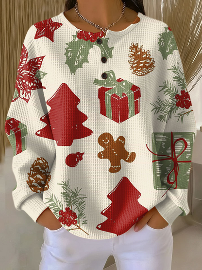 Benvit våffelstickad tröja med knappslå på modell, mönstrad med röda granar, paket, pepparkaksgubbe, kottar, järnek och julstjärna. 23