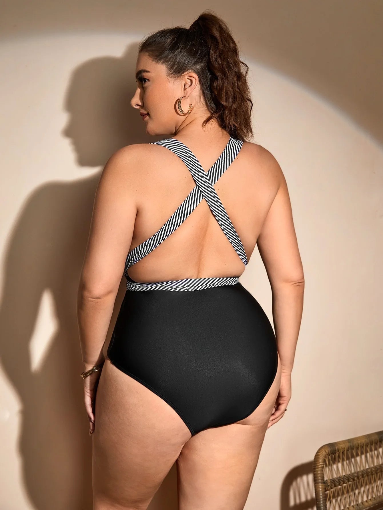 Frau im schwarzen Badeanzug mit gestreiften Trägern, Rückansicht, Plus-Size-Mode.