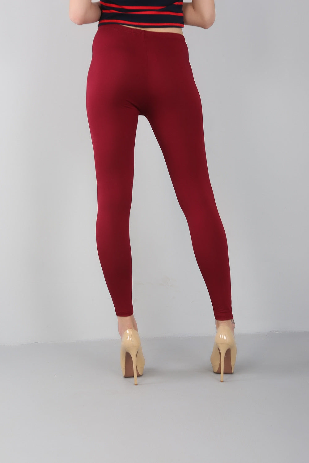 Frau in roten Leggings und beigen High Heels, Rückansicht, modisch, elegant, Damenmode.