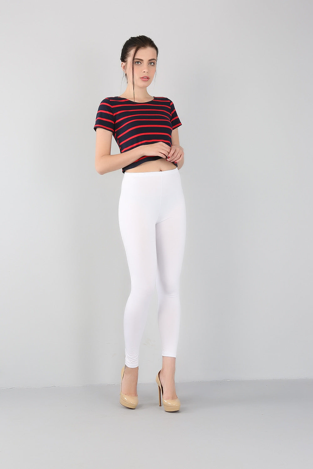 Frau in gestreiftem T-Shirt und weißen Leggings, beige High Heels, modisch, lässig.