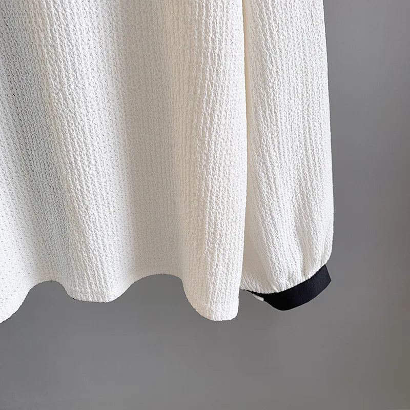 Weiße Strickjacke mit schwarzem Saum, Textur, Damenmode, elegant, modern, stilvoll.