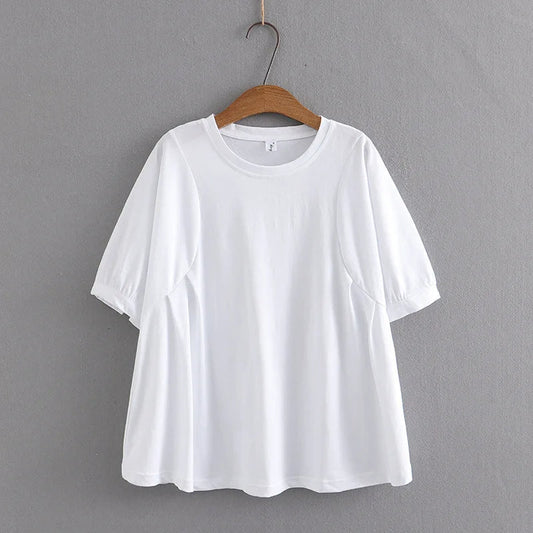 Weißes Damen-T-Shirt aus Baumwolle, kurzärmelig, auf Holzkleiderbügel vor grauer Wand.