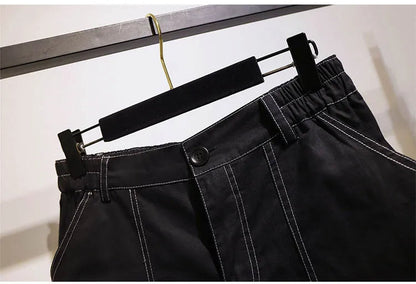 Schwarze Hose mit weißen Nähten, elastischer Bund, Knopfverschluss, auf Kleiderbügel.