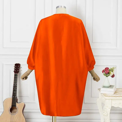 Orangefarbener Kimono aus Satin, Rückansicht, auf Schneiderpuppe, neben Gitarre und Blumen.