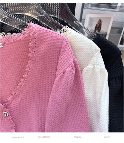 Rosa, weiße und schwarze Blusen aus Waffelstoff mit Spitzenbesatz auf Kleiderbügeln.