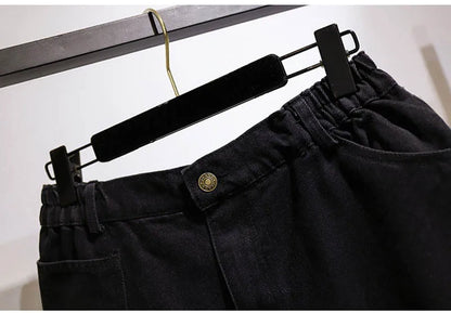 Schwarze Jeanshose mit elastischem Bund, Knopfverschluss, auf Kleiderbügel, modisch, bequem.