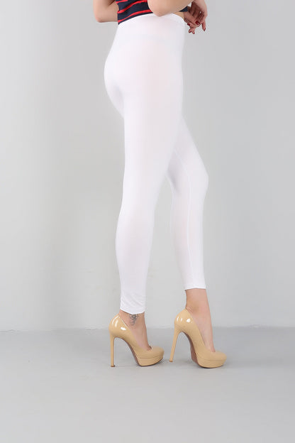 Frau in weißen Leggings und beigen High Heels, seitliche Ansicht, Modefotografie.