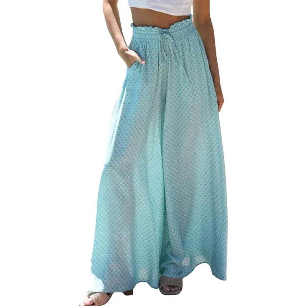 Frau in blauer, weit geschnittener Sommerhose mit Muster und weißem Top.