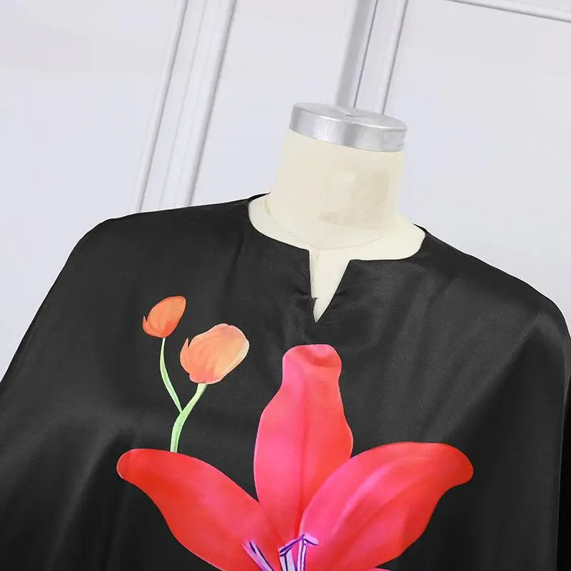 Schwarzes Seidenkleid mit rotem Blumenmuster auf Schneiderpuppe, elegantes Design.