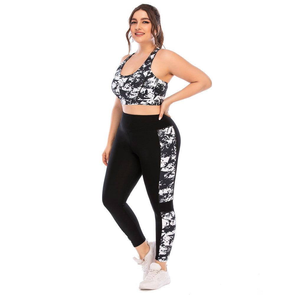 Frau in schwarz-weißem Sport-BH und Leggings, Fitnessmode, Plus-Size, lächelnd, Studioaufnahme.