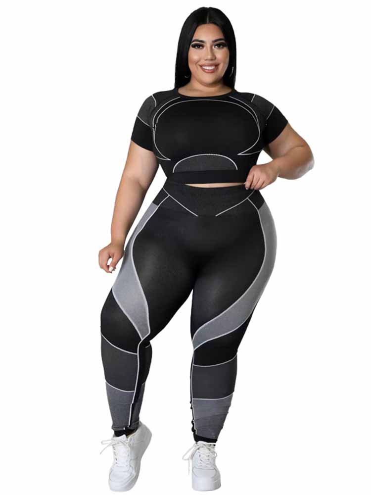 Frau in schwarzem Sport-Set mit grauen Akzenten, Plus-Size, Fitnessmode, lächelnd.