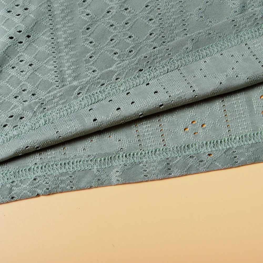 Grüner Spitzenstoff, geometrisches Muster, weiche Textur, ideal für Bekleidung und Dekoration.