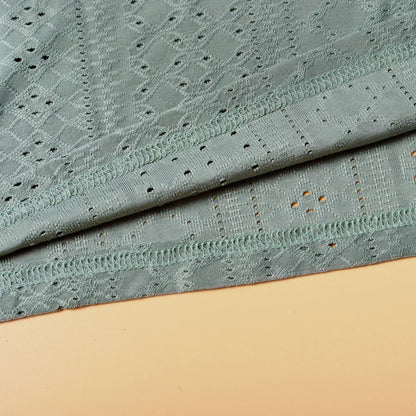 Grüner Spitzenstoff, geometrisches Muster, weiche Textur, ideal für Bekleidung und Dekoration.