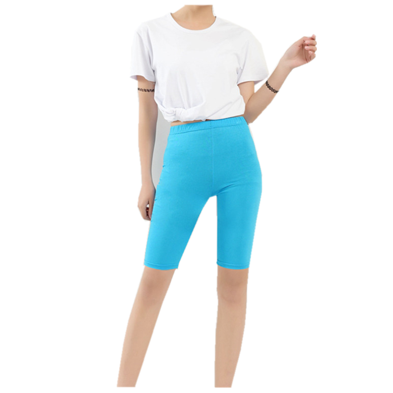 Frau in weißem T-Shirt und blauer Radlerhose, modische Freizeitkleidung.
