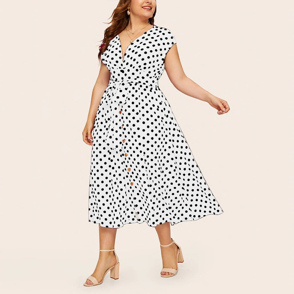 Frau im weißen gepunkteten Sommerkleid, knielang, mit Sandalen, lächelnd.