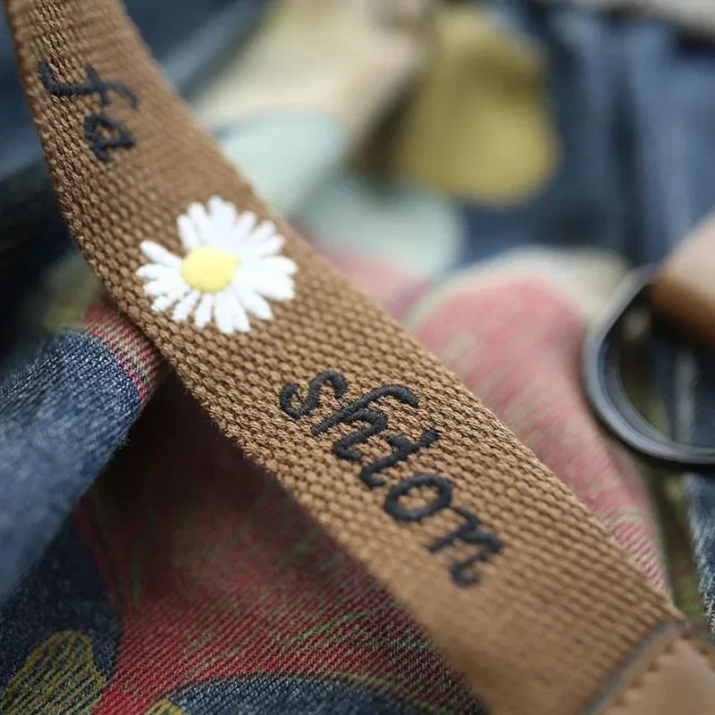 Brauner Stoffgurt mit Gänseblümchen-Stickerei und "fashion" Schriftzug, Nahaufnahme.