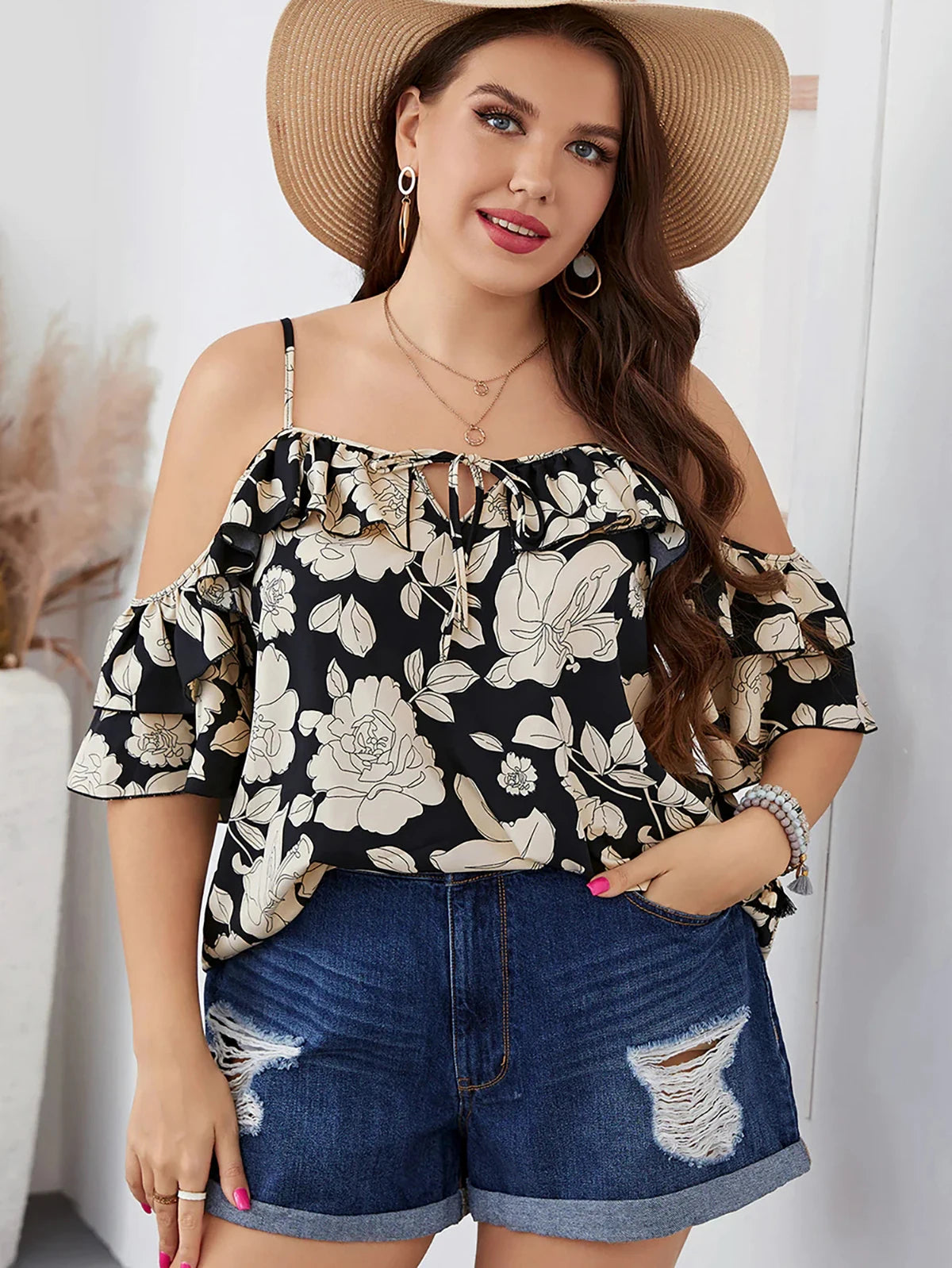 Frau in schwarzer Blumenbluse und Jeansshorts, Strohhut, lächelnd, Sommermode, Freizeitkleidung.