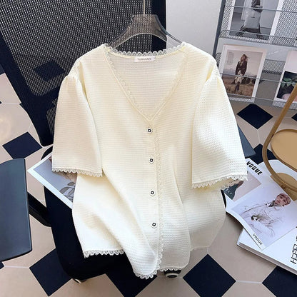 Weiße Strickjacke mit Knöpfen, V-Ausschnitt, Spitzenbesatz, Damenmode, elegant, auf Stuhl.