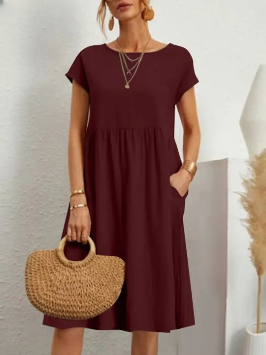 Frau in burgunderrotem Sommerkleid mit Strohtasche, elegantes Outfit, Modeaccessoires.