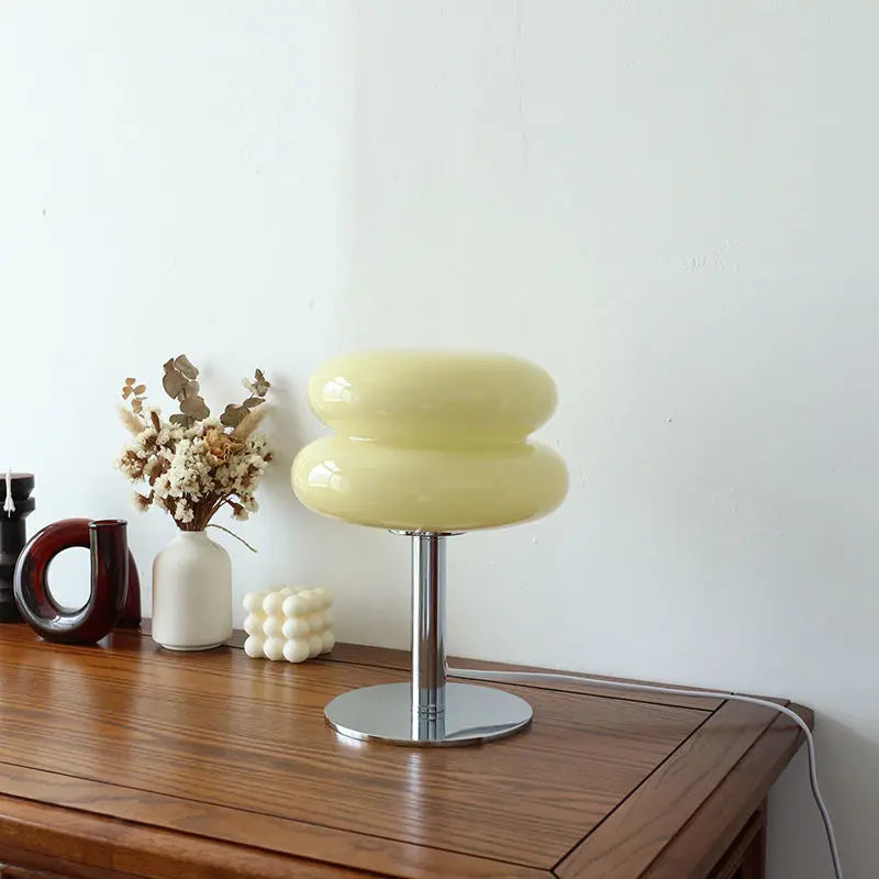 Gelbe Tischlampe aus Glas auf Holztisch, moderne Inneneinrichtung, dekorative Beleuchtung.