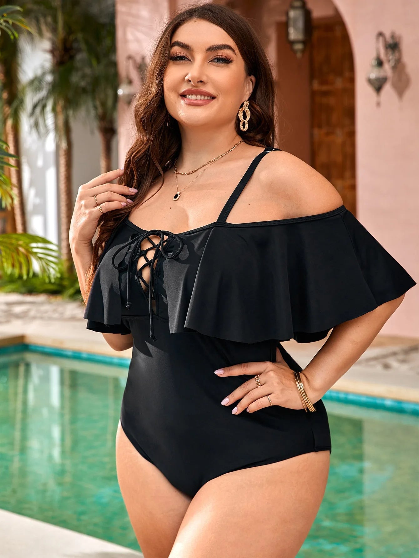 Frau im schwarzen Badeanzug mit Rüschen am Pool, Sommermode, eleganter Einteiler.