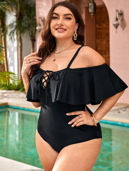 Frau im schwarzen Badeanzug mit Rüschen am Pool, Sommermode, eleganter Einteiler.